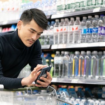 Man using phone while shopping for bottled water.