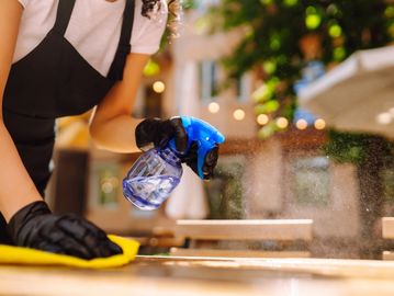 Person cleaning a surface with a spray bottle and cloth.