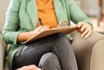 Therapist taking notes while listening to a patient in a comfortable setting.