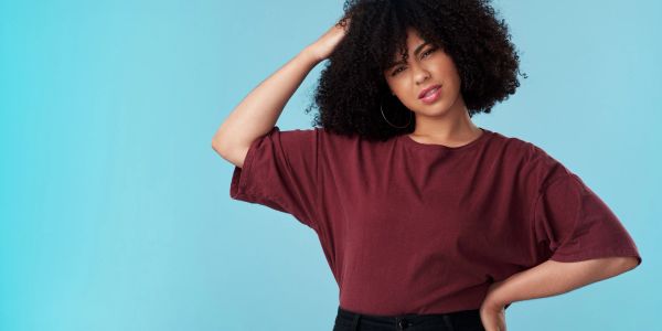 Woman with curly hair looks confused scratching her head.