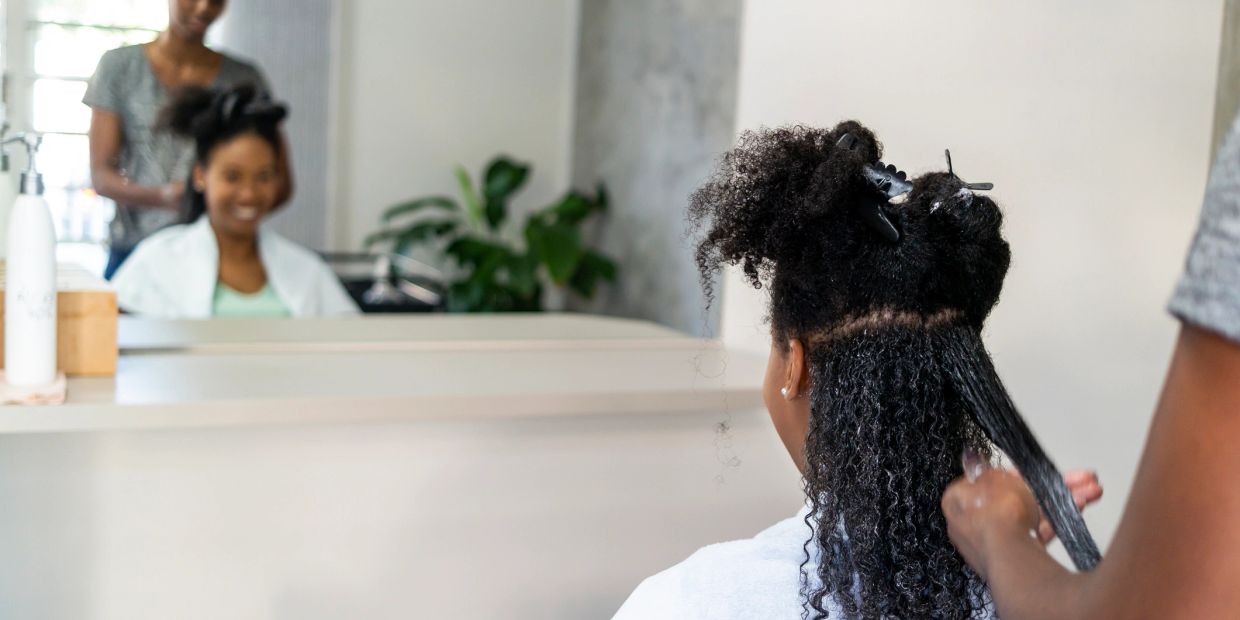 Woman getting her curly hair styled in a salon.