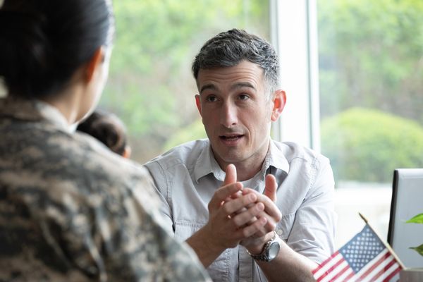 Man talking to a woman in military uniform indoors.