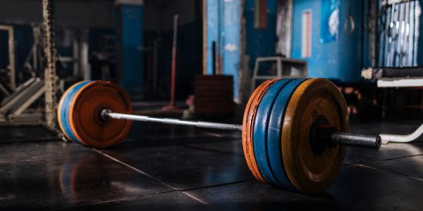 Loaded barbell resting on gym floor with colorful weight plates.