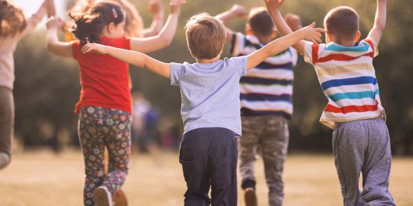 Children playing outdoors with arms raised.