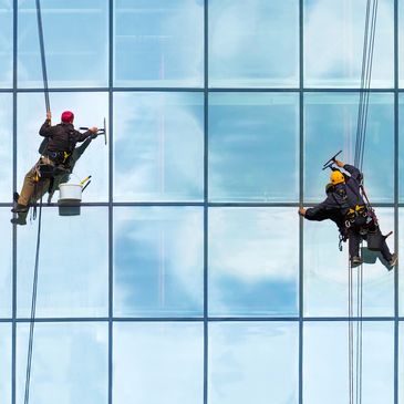 techniciens en accès sur corde effectuant du lavage de vitres en hauteur