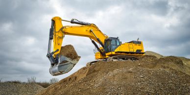 Yellow excavator moving dirt at construction site.