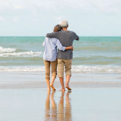 Senior couple walking together along a peaceful beach, enjoying worry-free living with trusted home 
