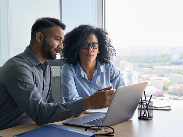 A man and woman looking at a laptop.