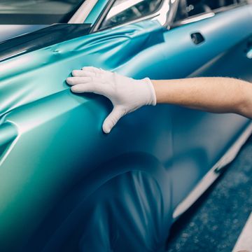 Person applying teal car wrap smoothly.
