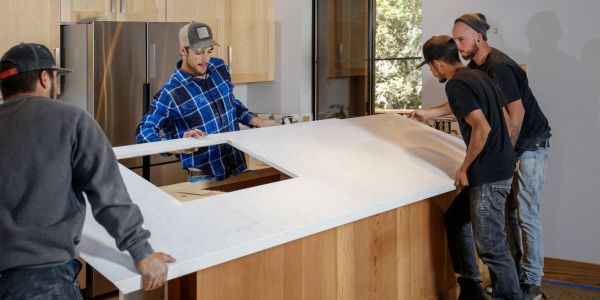 Four men install a kitchen countertop.