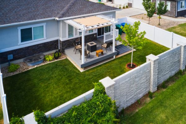 A backyard with a patio and white fence enclosure.