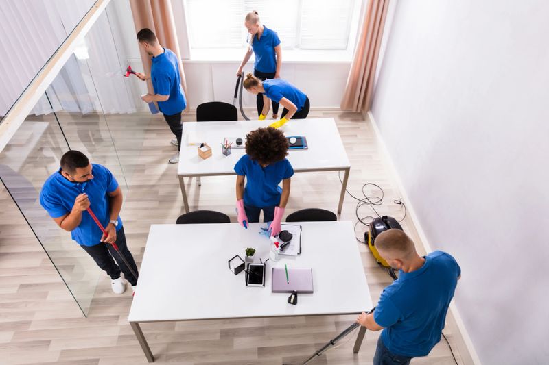High Angle View Of Janitors In Uniform Cleaning Modern Office