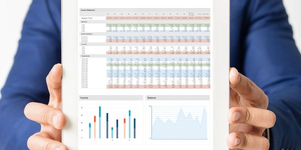 Businessman holding a tablet displaying financial analysis charts and data.