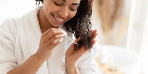 Woman applying hair oil with a dropper.