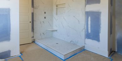 Modern walk in shower with marble tile walls and bench during bathroom renovation project.