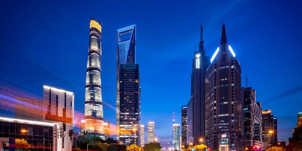 Nighttime cityscape with illuminated skyscrapers and streaks of car lights.