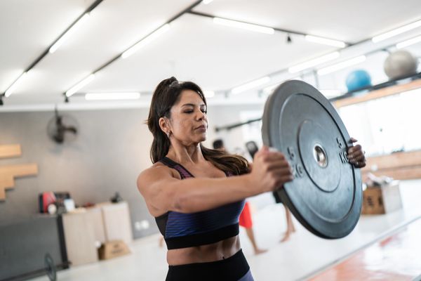 Woman lifting a weight plate in a gym workout.