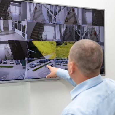 Man monitors security cameras on a large screen.