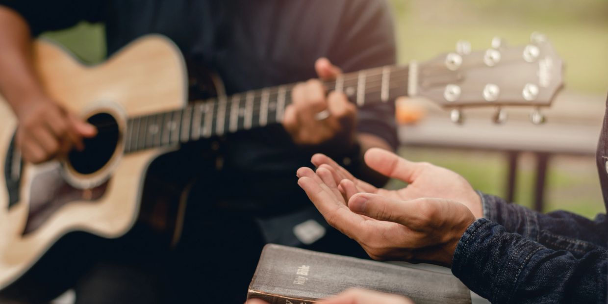 Person playing guitar during a small gathering.