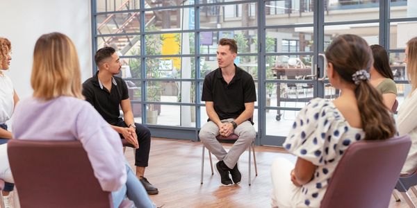 A group therapy session with six people sitting in a circle.