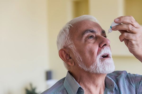Elderly man using eye drops.