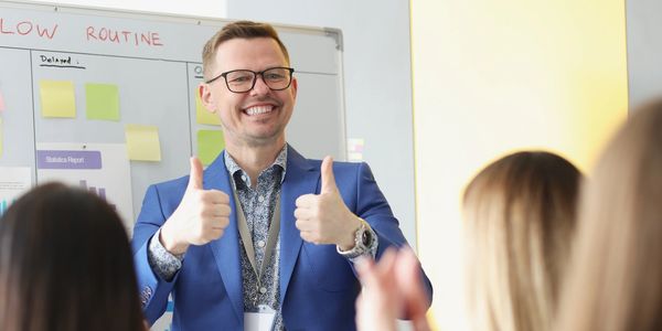 A smiley man holding both his thumbs up. 