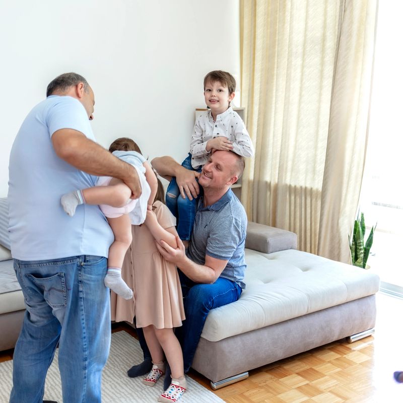 Cropped shot of an affectionate family of five on the sofa at home during the day. Family having fun together at home. Happy couple playing, having fun, hugging with their kids at home. Copy space.