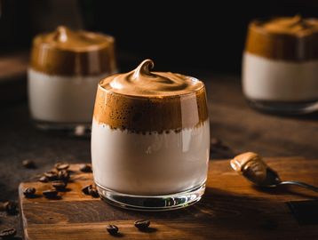 Creamy whipped coffee on milk in a glass.