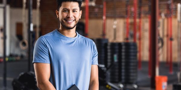Man smiling in a gym wearing a blue shirt.