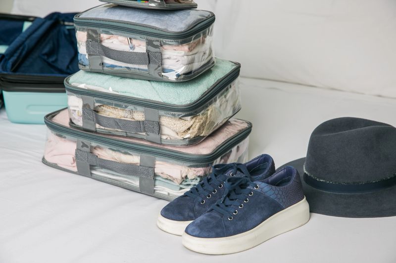 Woman packing for vacation using packing cubes in a suitcase