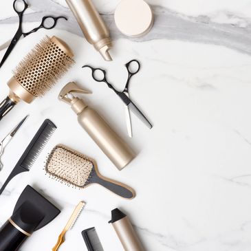 Hair styling tools and products arranged on a marble surface.