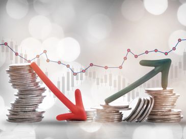 Stacked coins with red downward and green upward arrows showing financial trends.