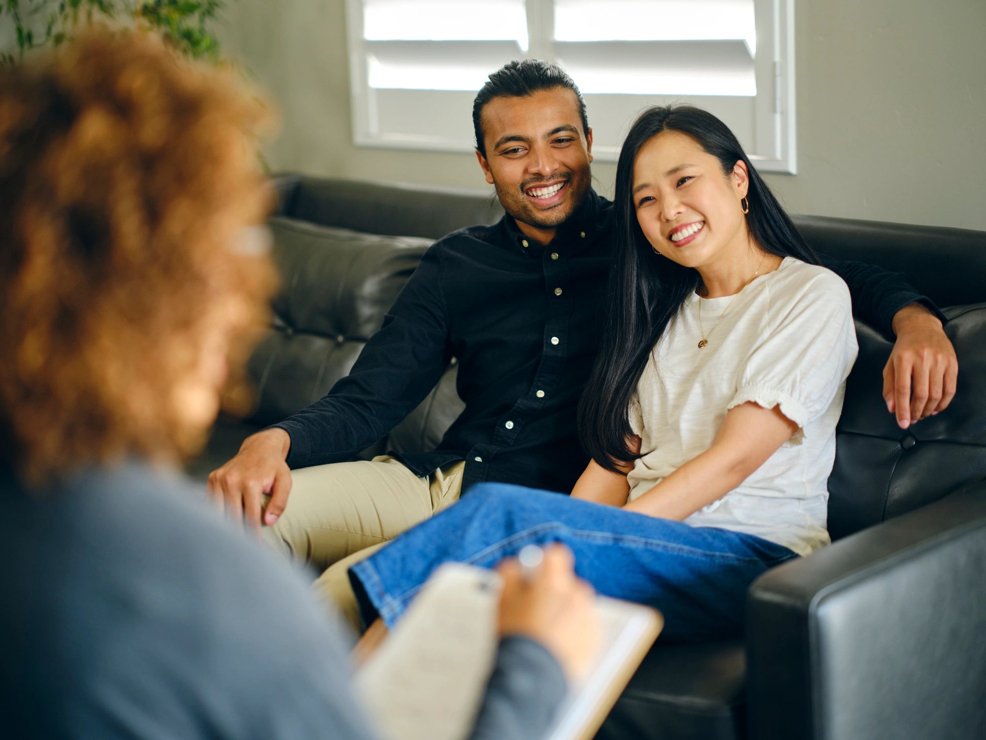 Happy couple smiling during a therapy session on a couch.