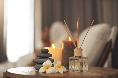 A candle, flowers and some candles on a table.