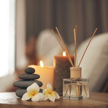 Spa setup with candles, stones, flowers, and reed diffuser.