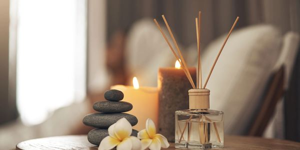 Aromatherapy setup with candles, stones, and flowers on a wooden table.