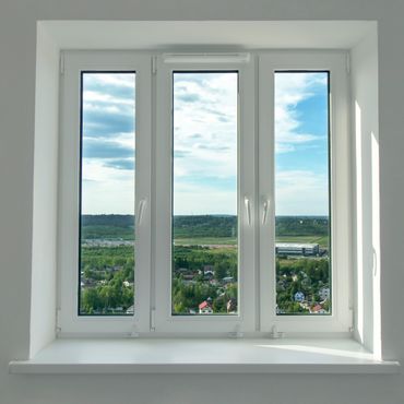 View of a green landscape and houses through a clean white window frame.
