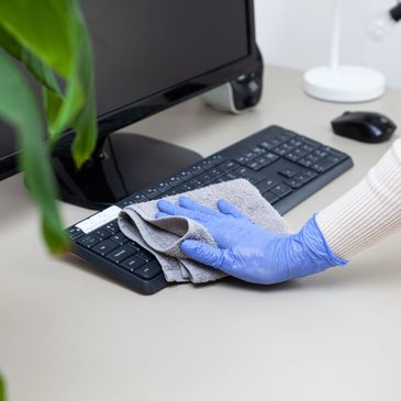 Hand with glove cleaning keyboard with cloth.