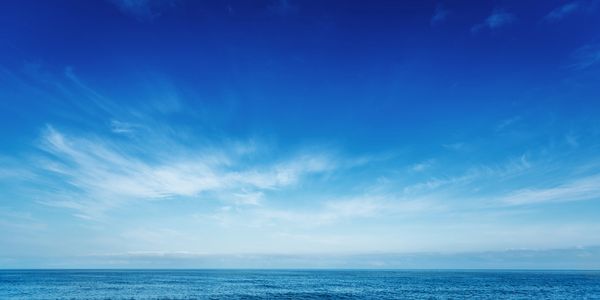 Clear blue sky over calm ocean water on a sunny day.
