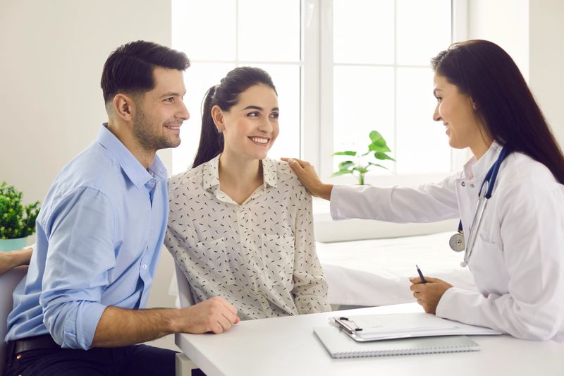 Female doctor consulting young couple patients in fertility clinic about IVF or IUI. Doctor encourages and assures the young couple that everything will be fine. Concept of artificial insemination.