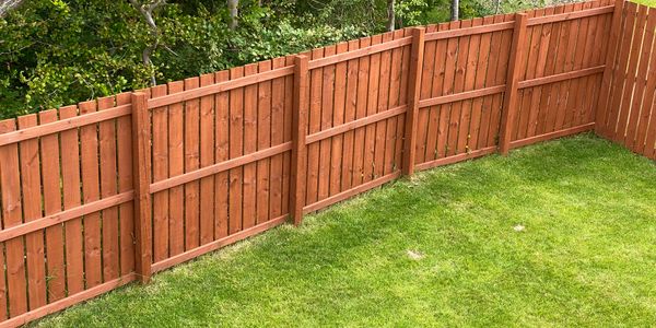 A neatly maintained backyard with a wooden fence and green grass.