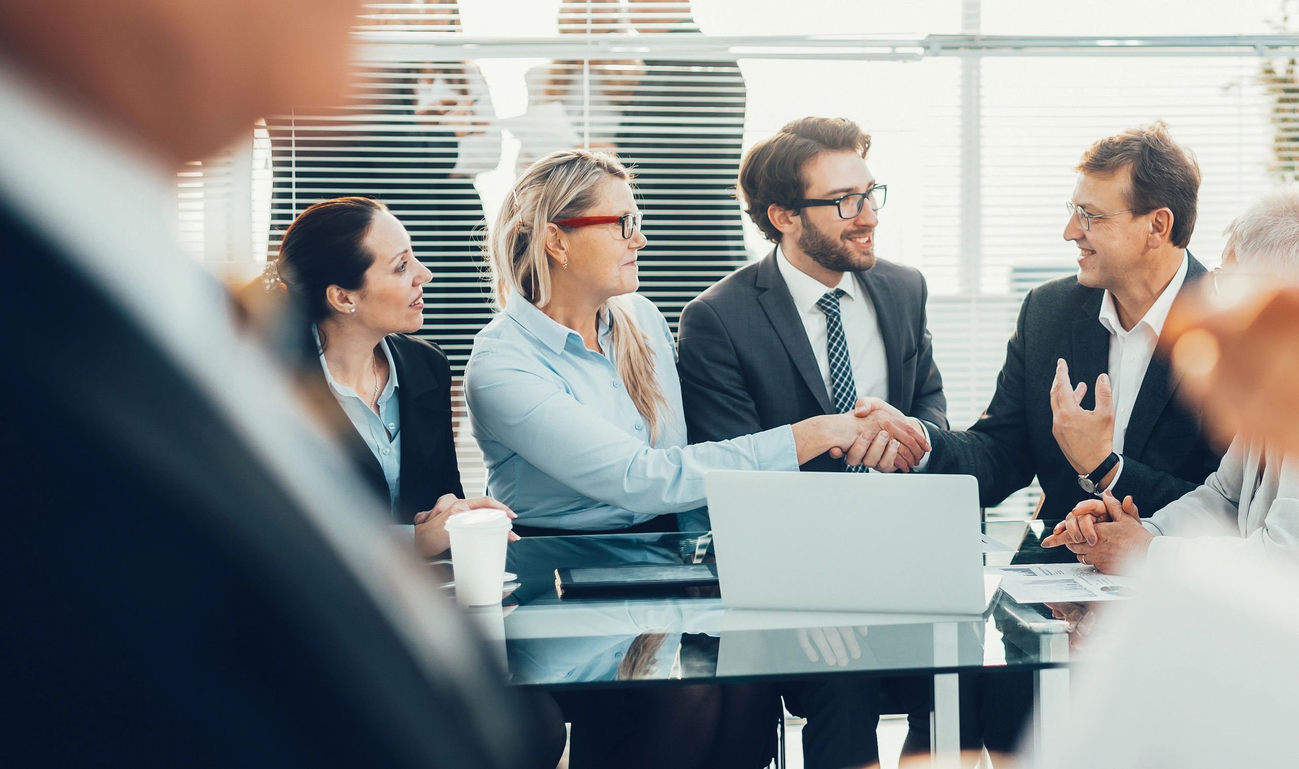 Business professionals shaking hands in a meeting, signaling agreement.