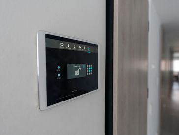 Black wall-mounted smart home panel displaying controls.