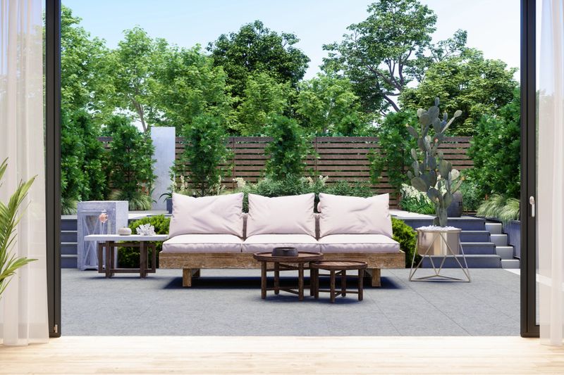 Patio With Sofa, Coffee Table, Cactus Plant And Garden View Background.