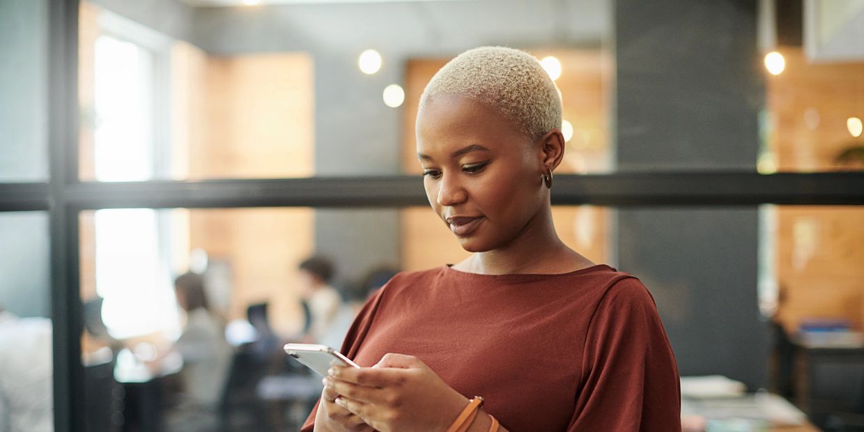 Woman with short blonde hair looking at phone indoors.