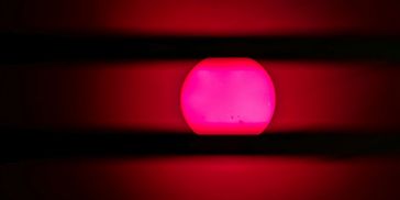 Bright pink sun setting between dark horizontal lines.