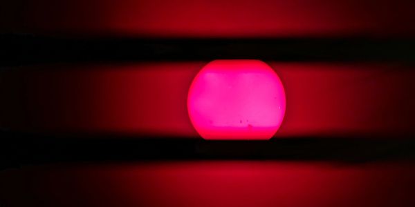 Bright pink sun setting between dark horizontal lines.