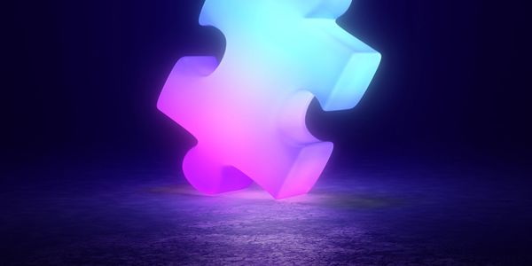 Glowing puzzle piece with blue and pink hues on a dark floor.