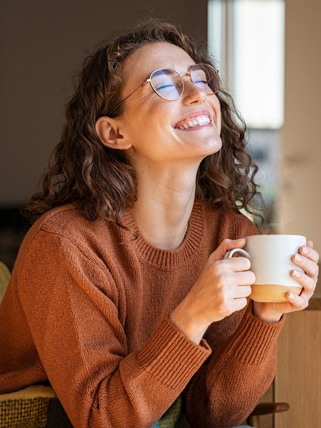 Woman drinking coffee and laughing following healing with trauma therapy, IFS, EMDR in Ohio.