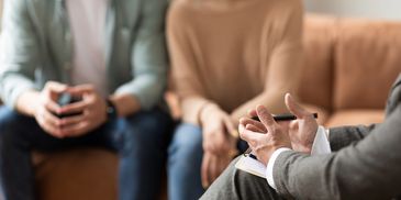 Couple in therapy session with counselor taking notes.